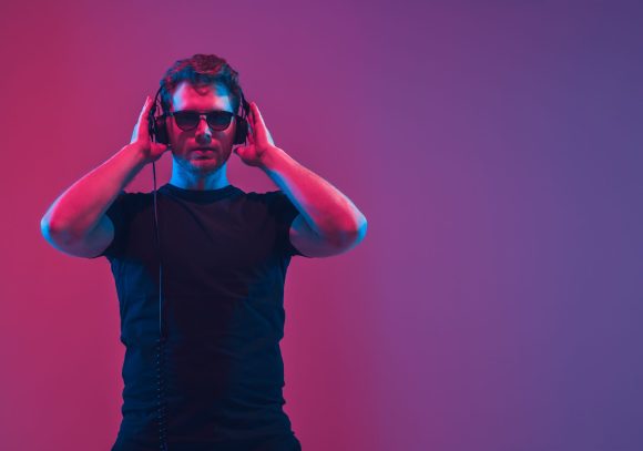 Young caucasian musician singing, dancing in neon light, flyer